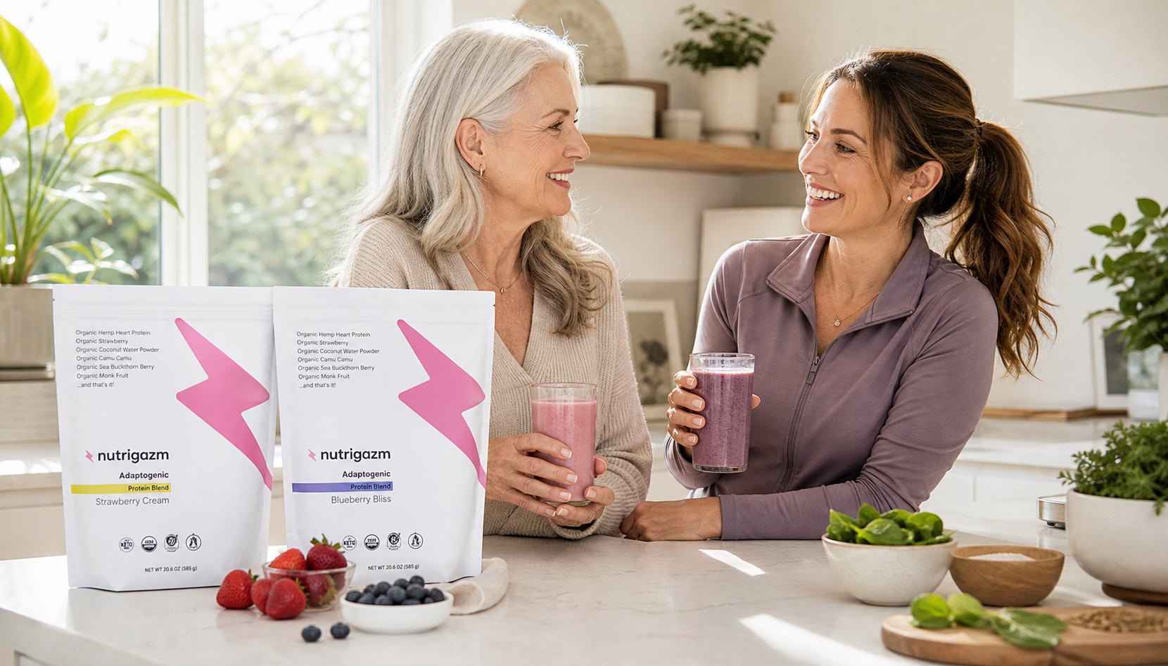 Older woman and younger woman smiling in natural kitchen light with Nutrigazm shakes and product bags on the counter